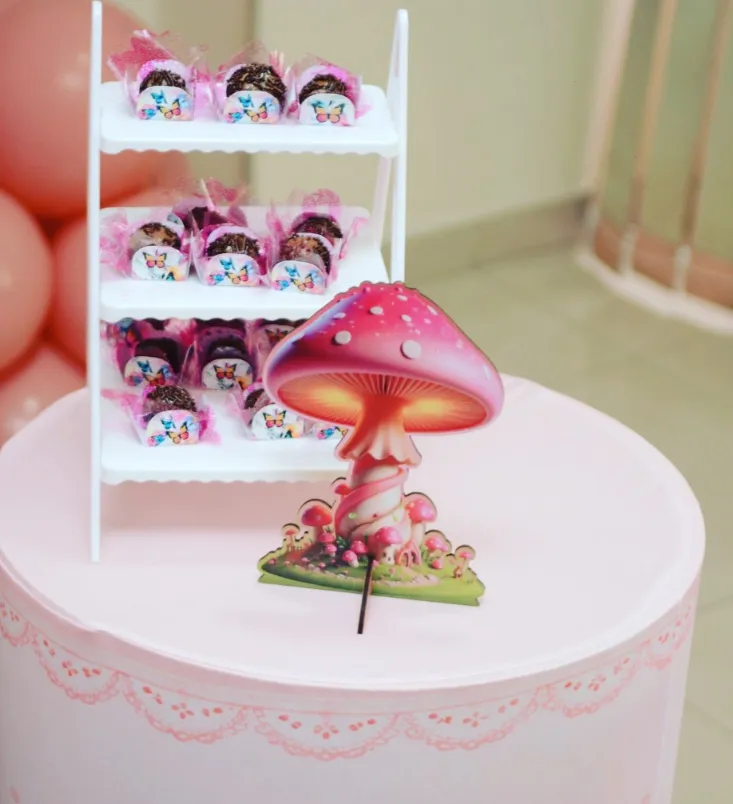 Cogumelo decorativo rosa em frente a expositor de brigadeiros personalizados